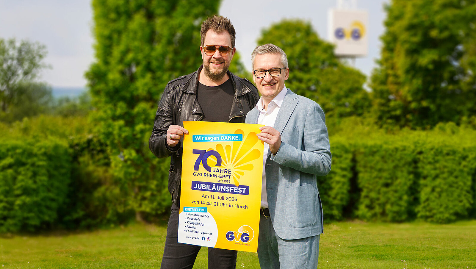 Werner Abromeit und Sven Welter halten ein Poster zum Jubiläumsfest 2026 in den Händen