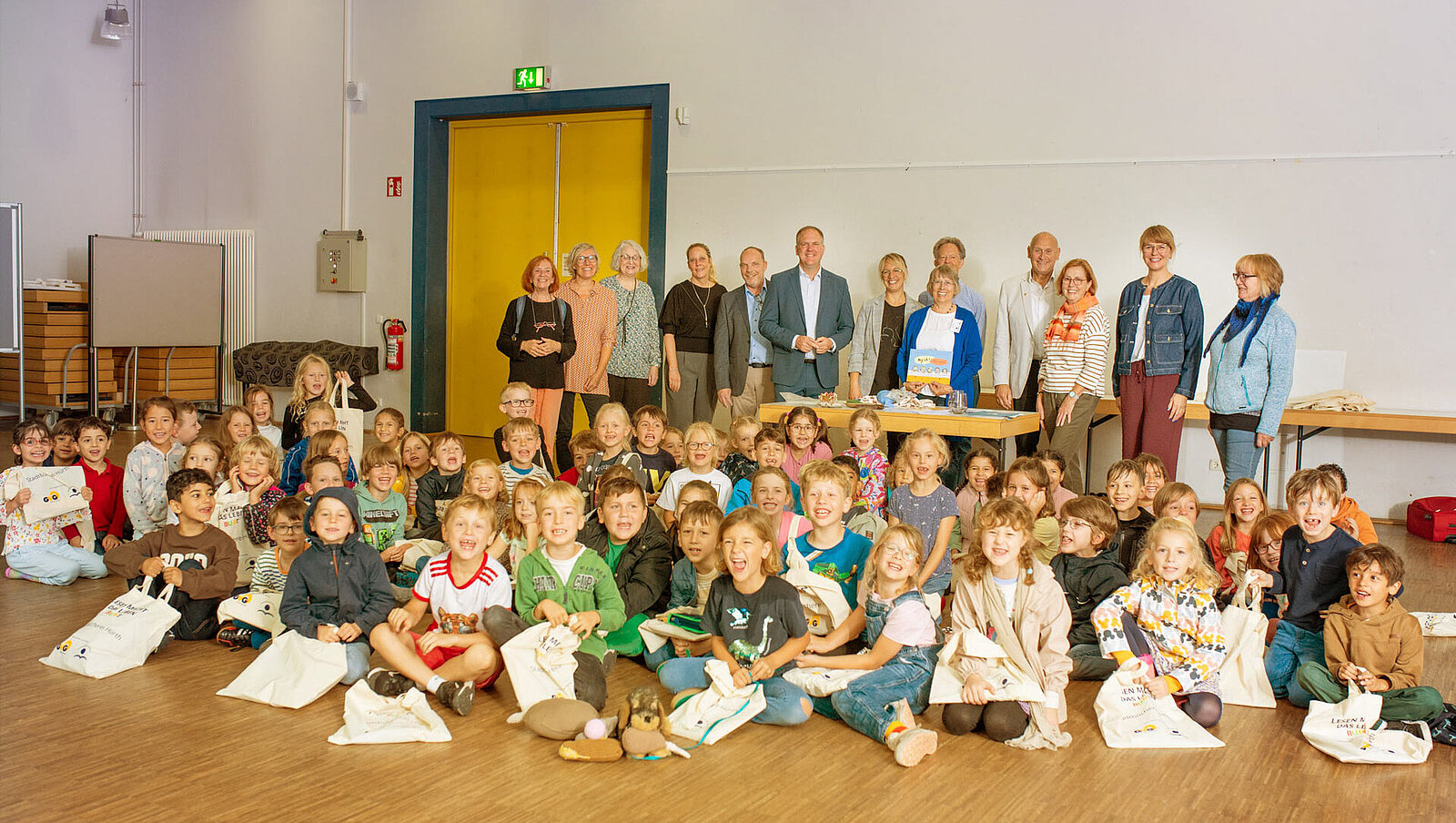 Eine Gruppe von Kindern und Lehrern. Vor den Kindern liegen GVG-Lesetaschen.
